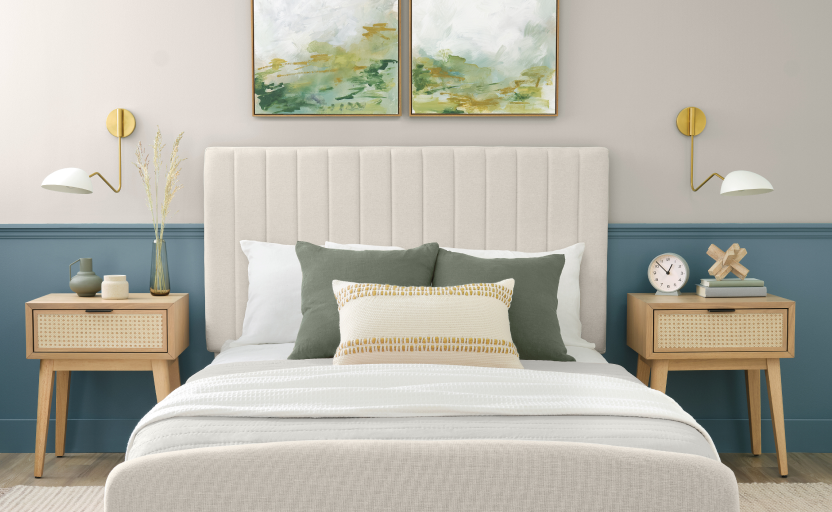 Bedroom with neutral and blue walls, neutral decor and nightstands, art above the bed with a couple throw pillows.